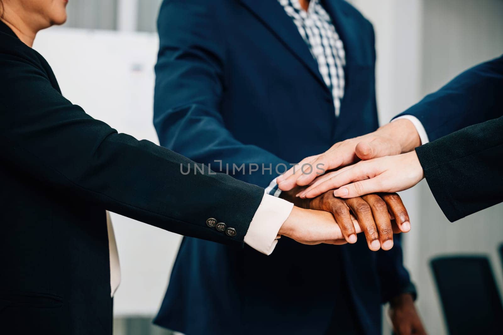 Businessmen and businesswomen celebrate their success with an above view of a hand-stacking ceremony. Their cheerful bonding reflects the spirit of cooperation and communication in the workplace.