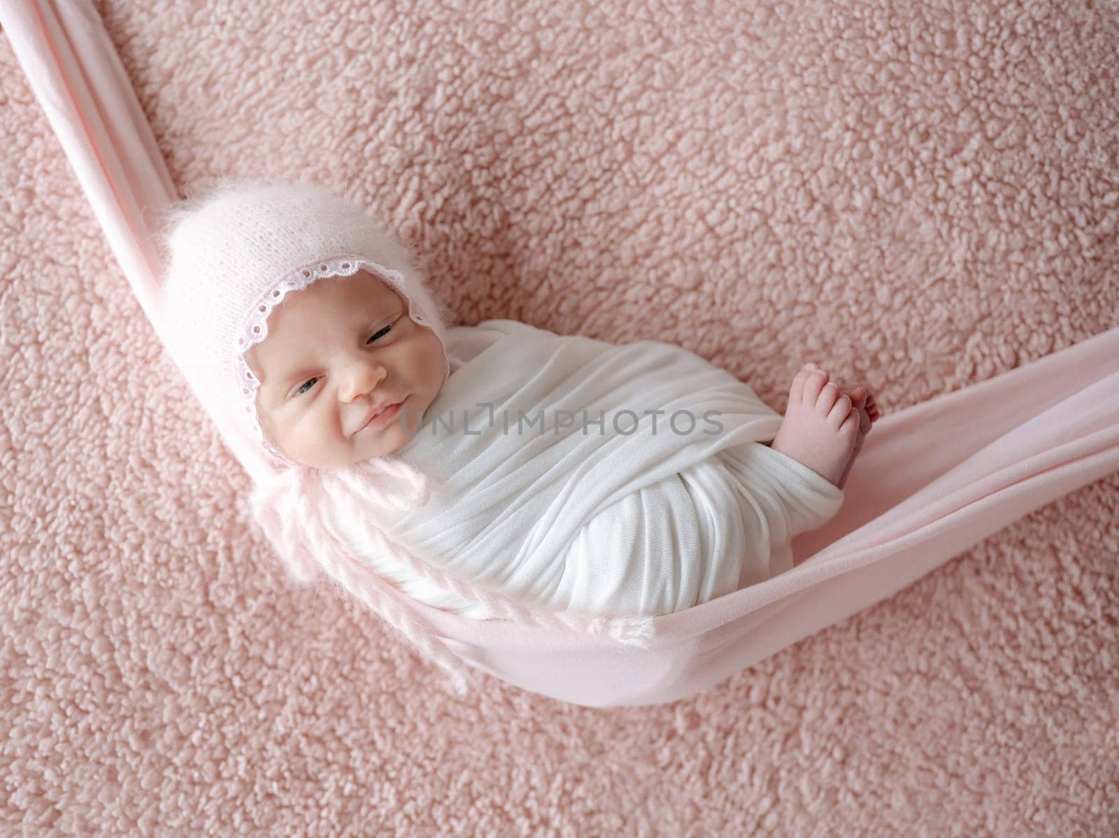 Newborn Baby Wrapped In Swaddle Sleeps In Hammock During Photoshoot With Smile by tan4ikk1