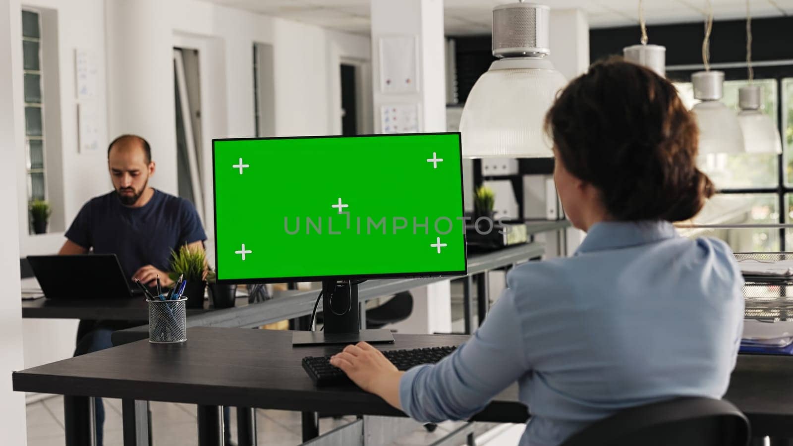 Analyst checks greenscreen desktop on pc, sitting in coworking space at agency office. Company worker examining computer monitor running blank copyspace with mockup screen. Handheld shot.