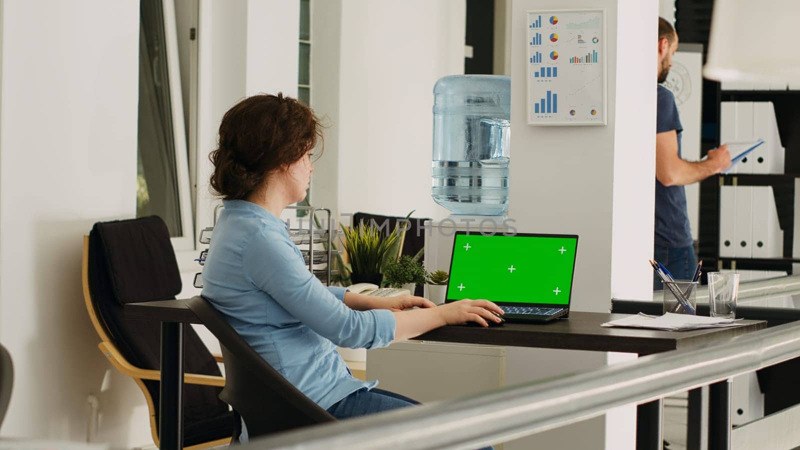 Office employee watches greenscreen on laptop display, working on small business operations at desk. Person looking at screen running isolated chromakey template with mockup copyspace.
