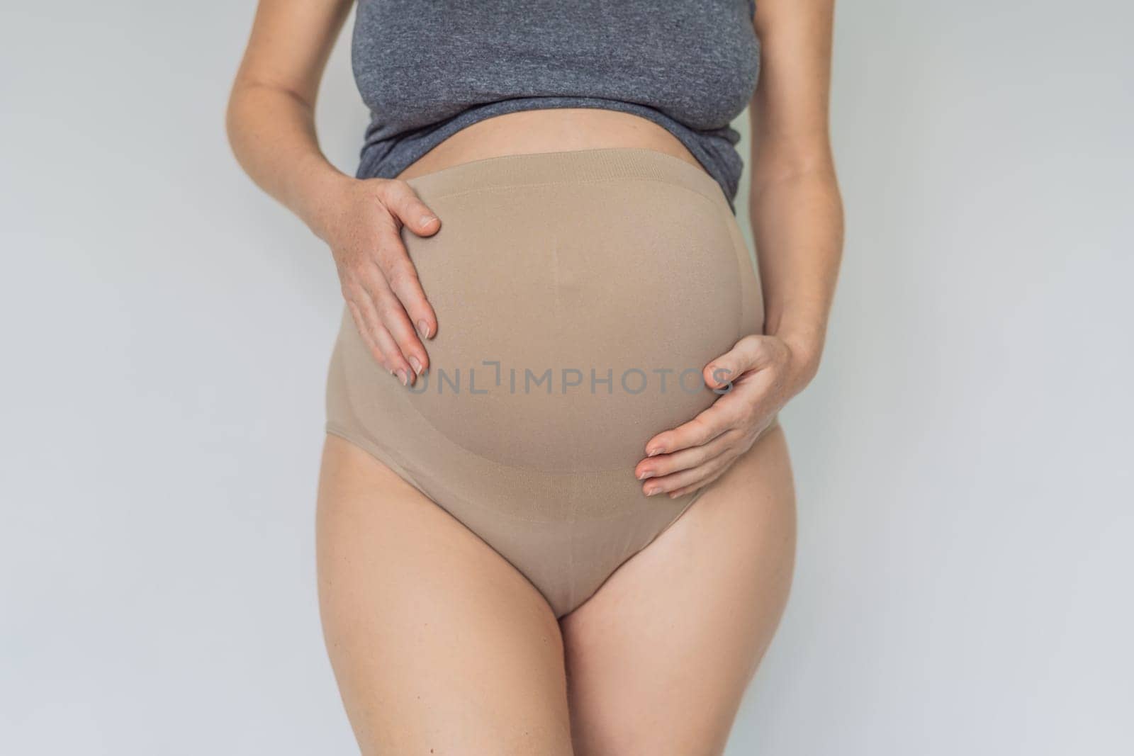 Pregnant bliss: Mom-to-be embraces her baby bump with a soft fabric bandage, providing gentle support. Maternity made comfortable.