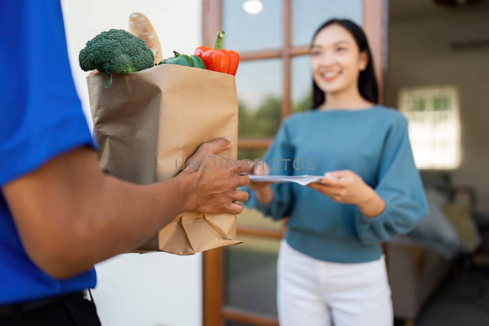 Asian young delivery man delivering package to female customer at home.