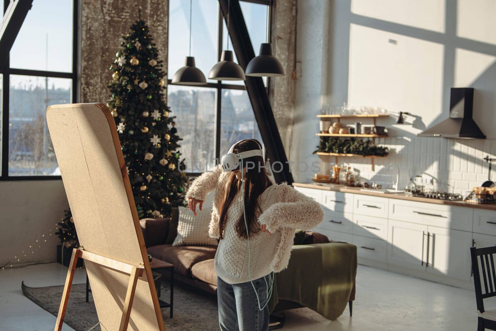 Engrossed in the holiday spirit, a young woman in light clothing and a virtual reality headset stands by the mirror. High quality photo