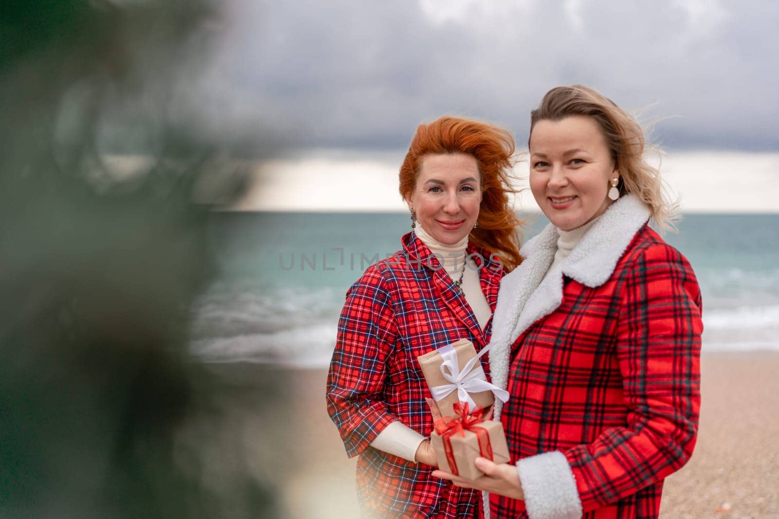 Sea two Lady in plaid shirt with a christmas tree in her hands enjoys beach. Coastal area. Christmas, New Year holidays concep by Matiunina