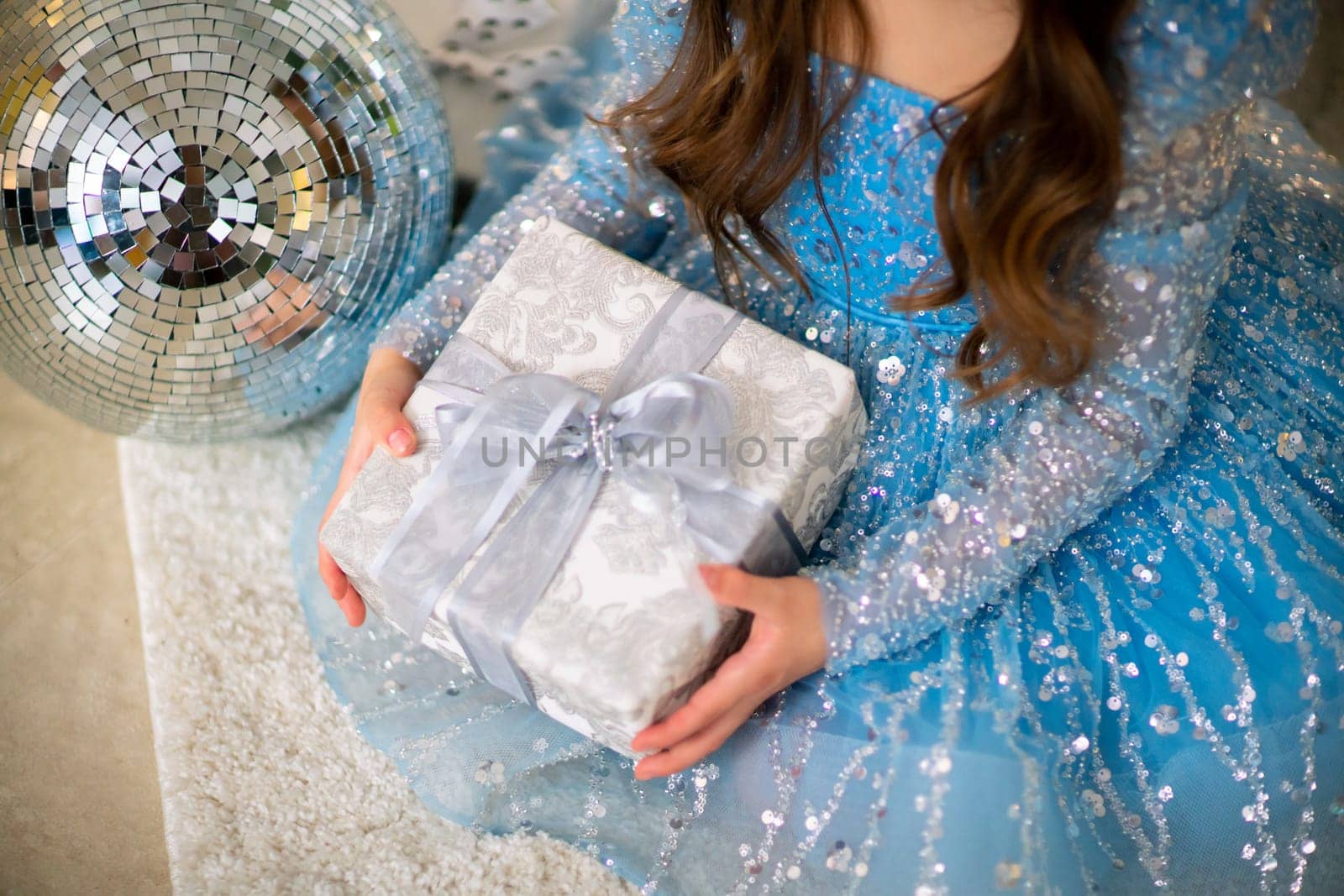 Female hands hold a gift box. Christmas, new year, birthday concept. The girl is dressed in a blue dress and holds out a gift