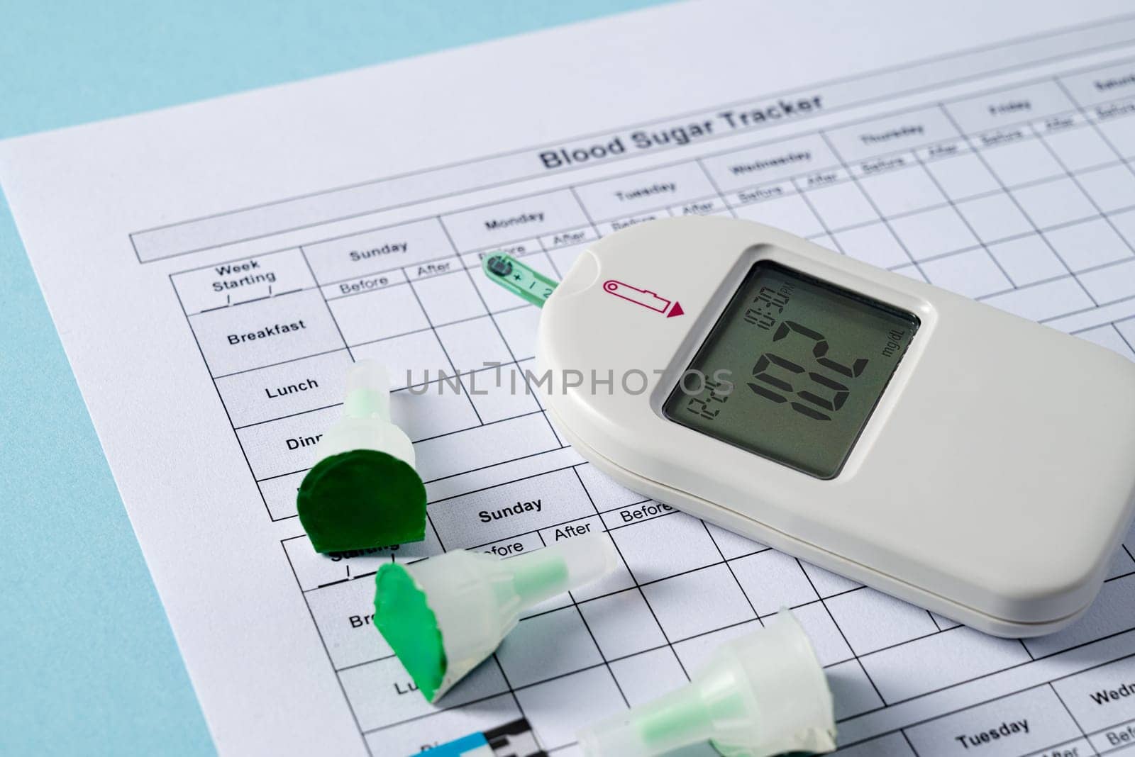 Top view of glucometer, lancet pen, strips and blood sugar tracker on blue background. diabetes test kit