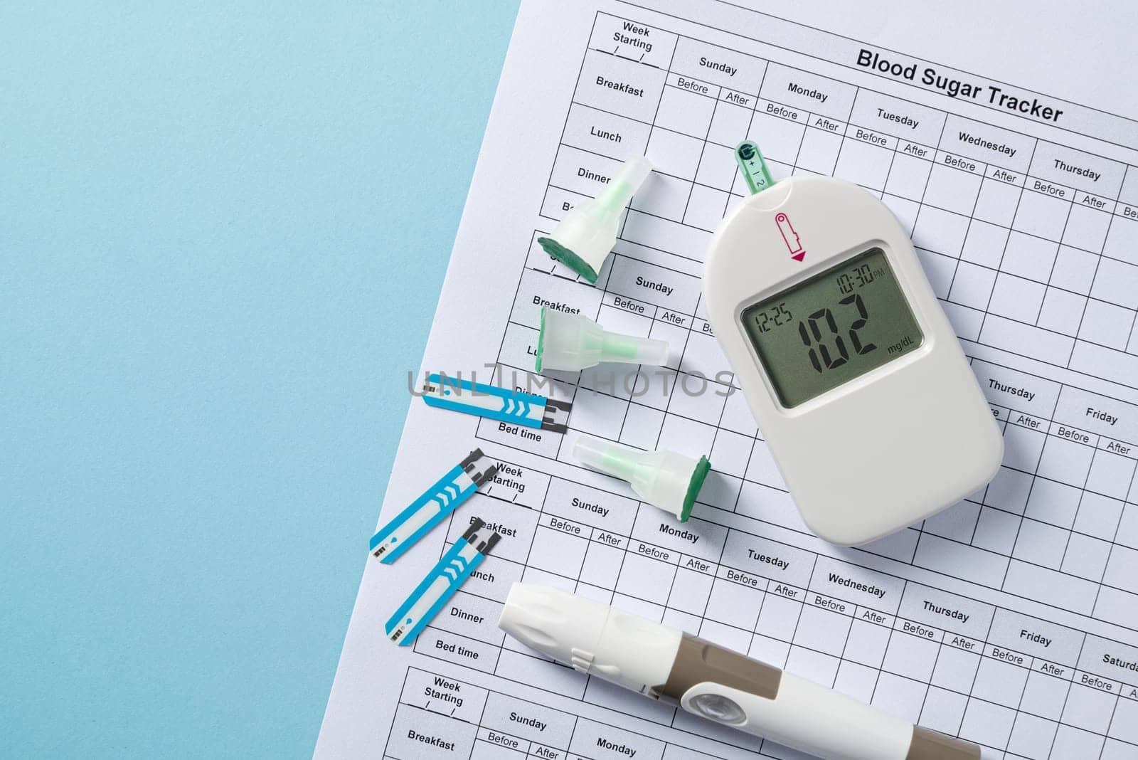 Top view of glucometer, lancet pen, strips and blood sugar tracker on blue background. diabetes test kit by Sonat