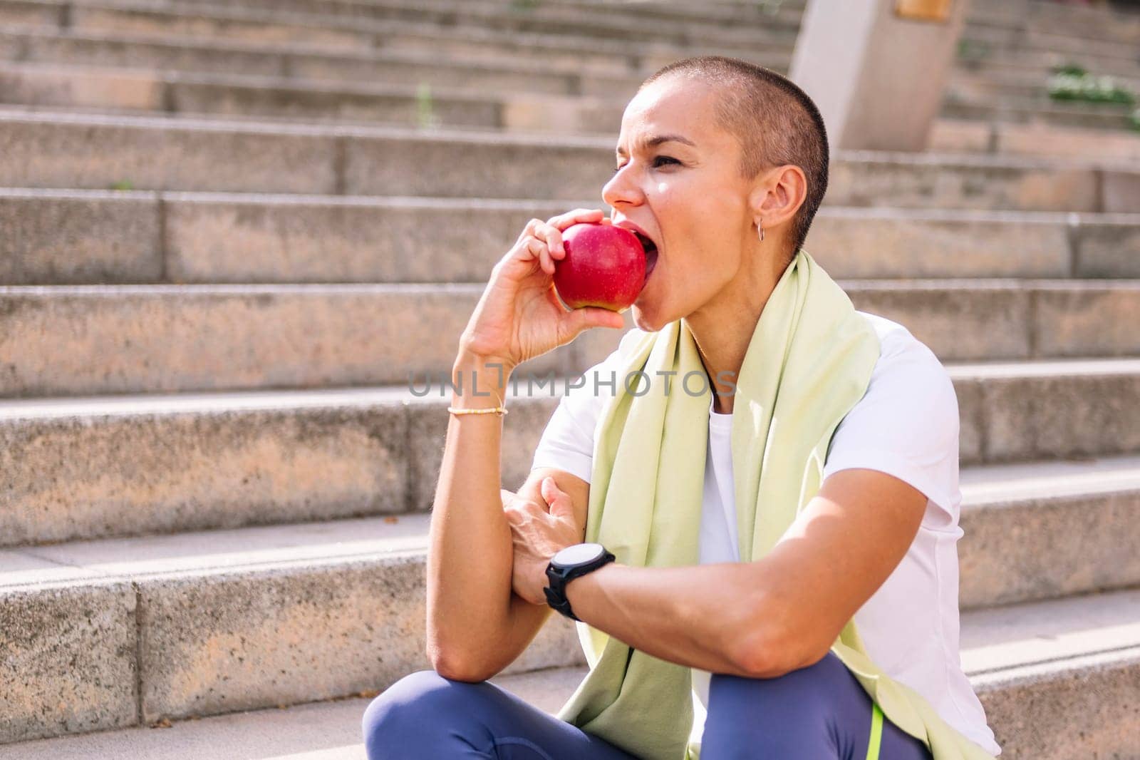 sports woman with short hair rests eating an apple by raulmelldo