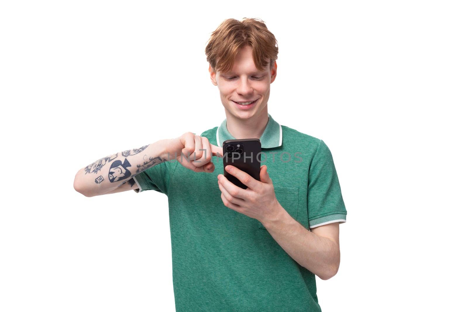 young caucasian man with red hair dressed in a green t-shirt shoots a video on the phone.