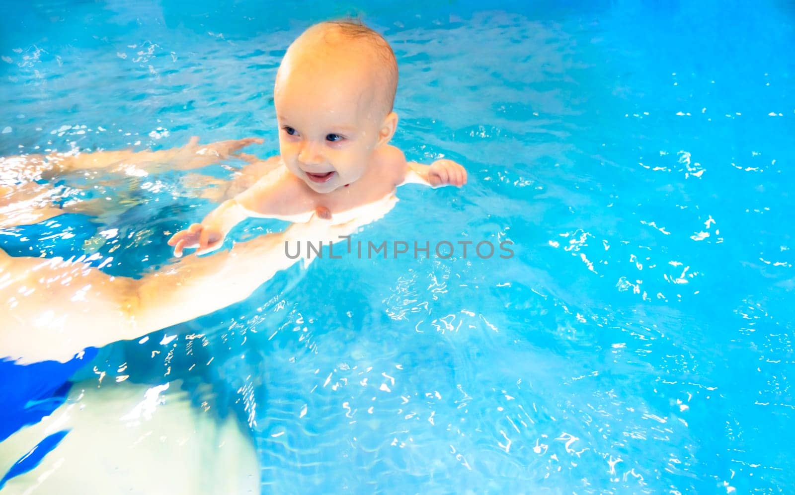 Adorable baby girl enjoying swimming in a pool with her mother early development class for infants teaching children to swim and dive. by kajasja