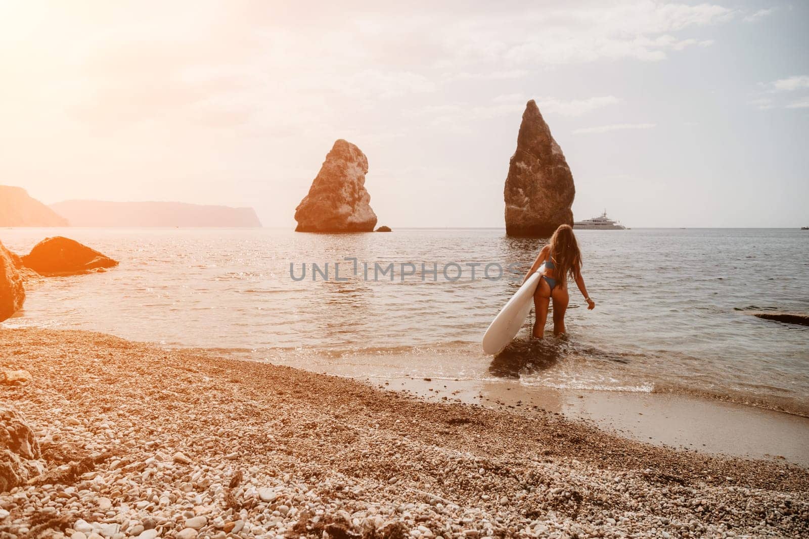 Close up shot of beautiful young caucasian woman with black hair and freckles looking at camera and smiling. Cute woman portrait in a pink bikini posing on a volcanic rock high above the sea