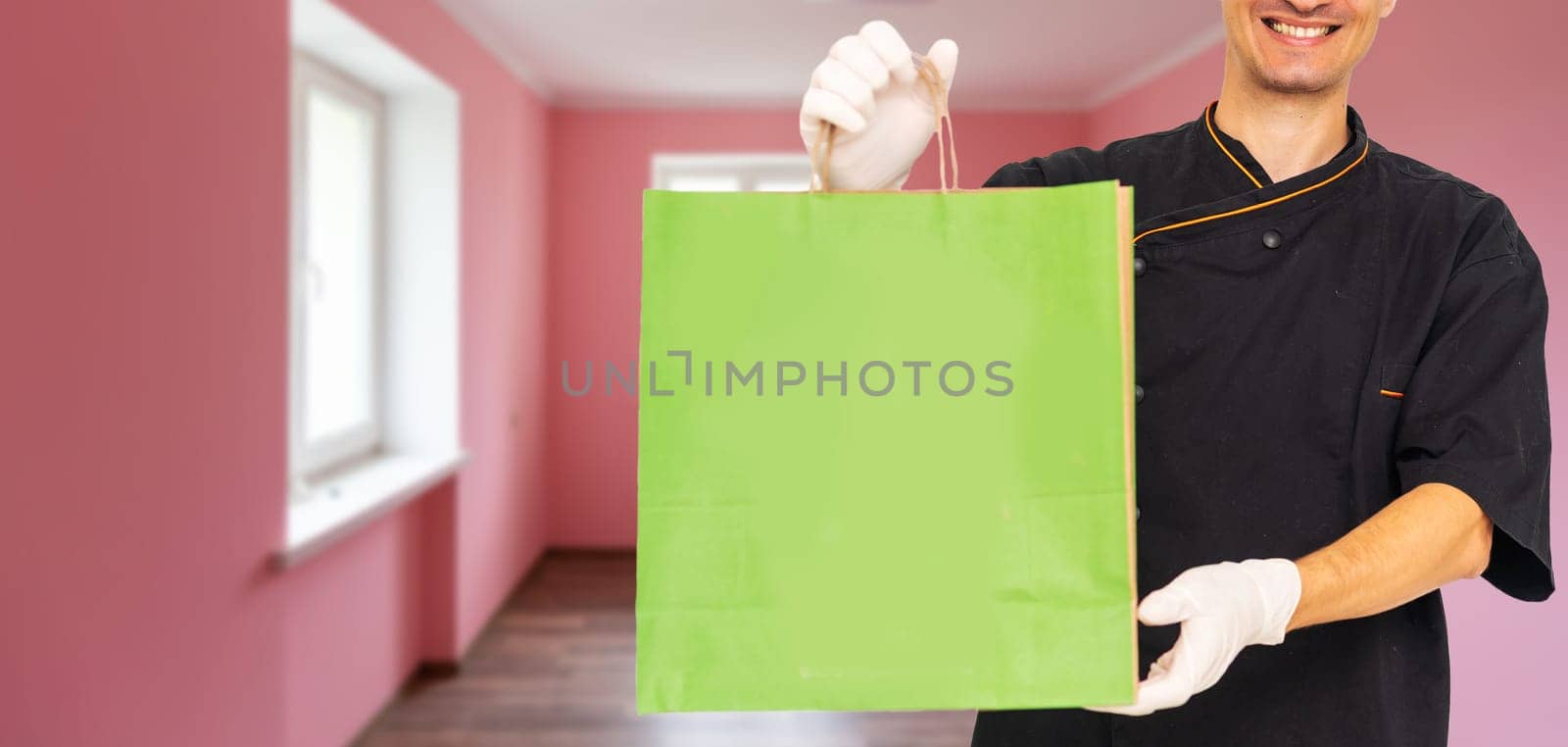 box with fast food being carried by delivery man in uniform for one of clients by Andelov13