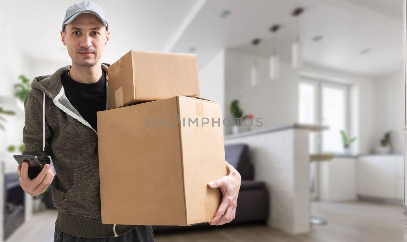 Smiling young delivery man holding and carrying a cardbox.