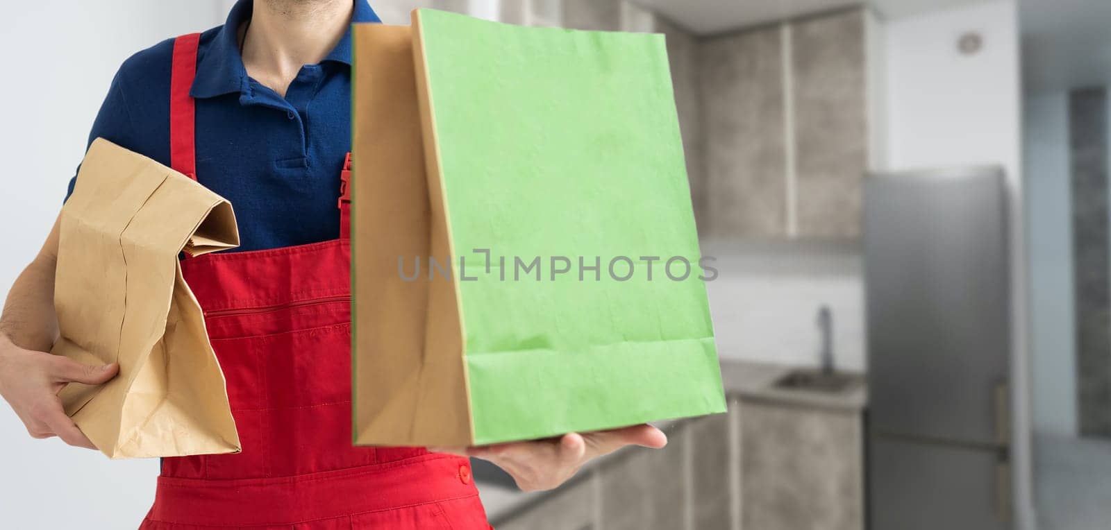 Courier holding paper bags with food, space for text. Delivery service by Andelov13