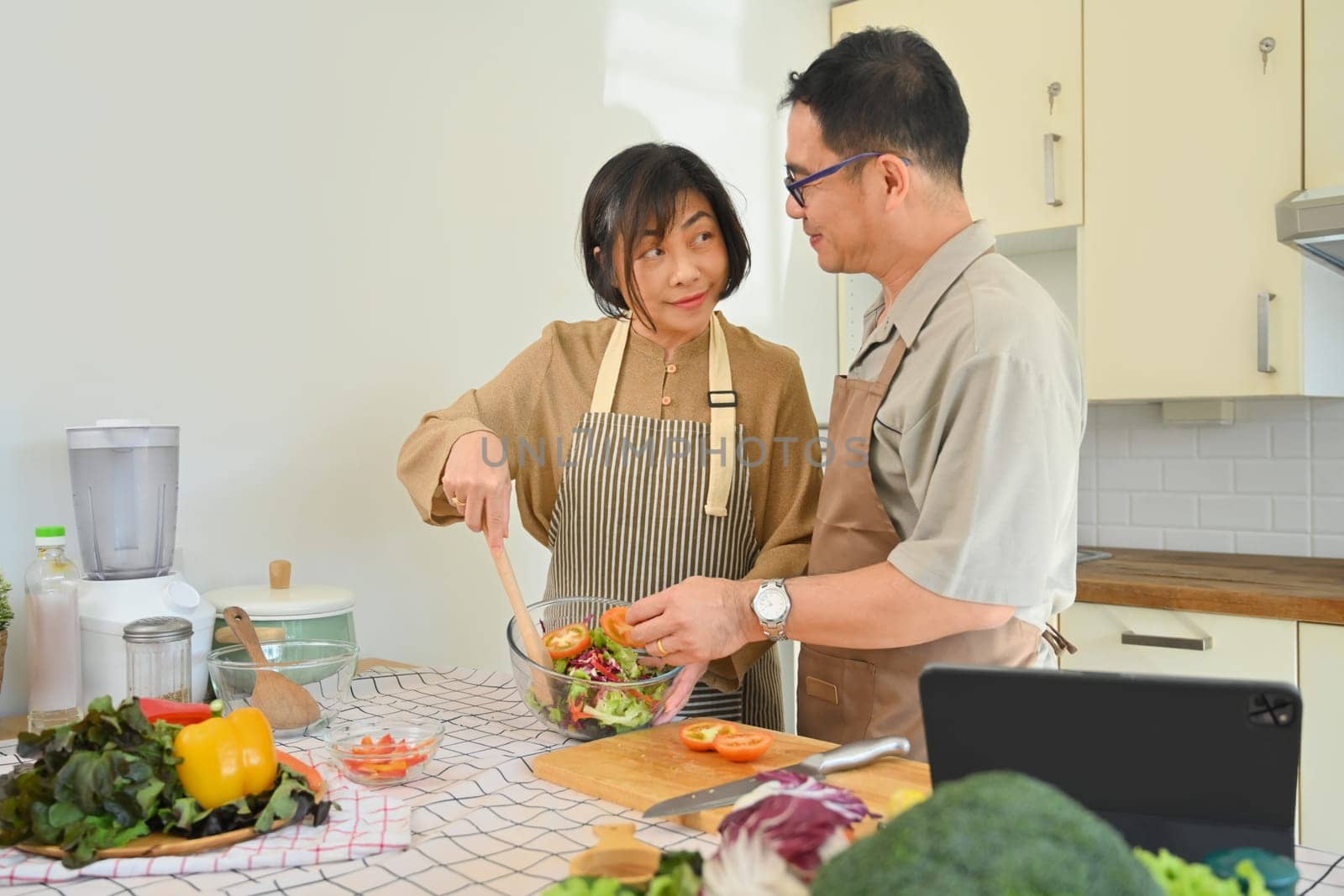 Shot of a happy senior couple cooking vegan vegetarian food meal in kitchen. Healthy eating concept
