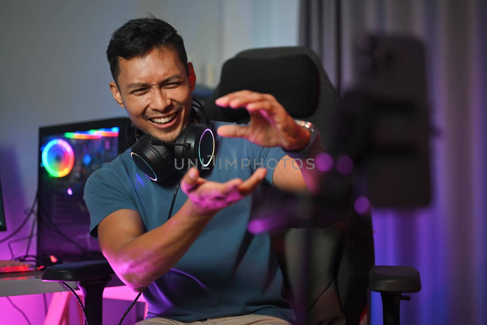 Professional gamer talking by microphone with audience while playing online video game. by prathanchorruangsak