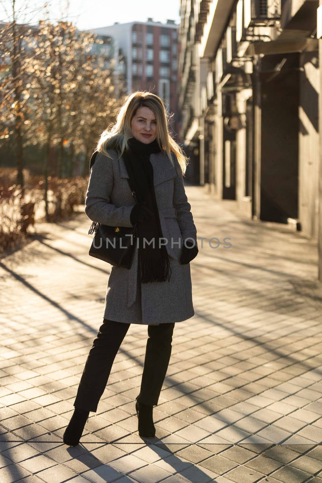 Young stylish hipster girl wearing modern trench coat walking in urban city smiling happy. Caucasian female model. Fall fashion. High quality photo