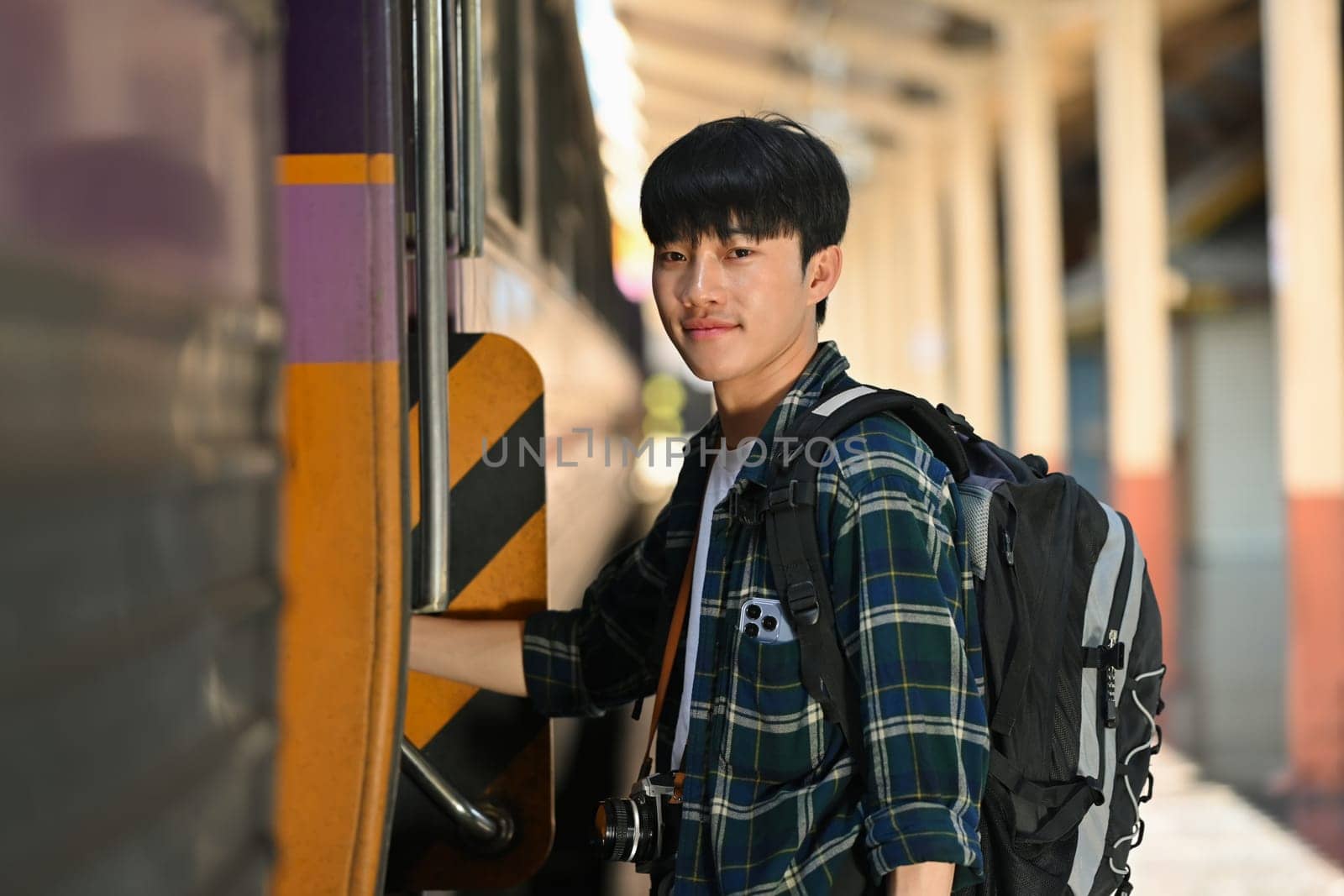 Handsome male traveler with a backpack getting on the train. Travel and vacations concept by prathanchorruangsak