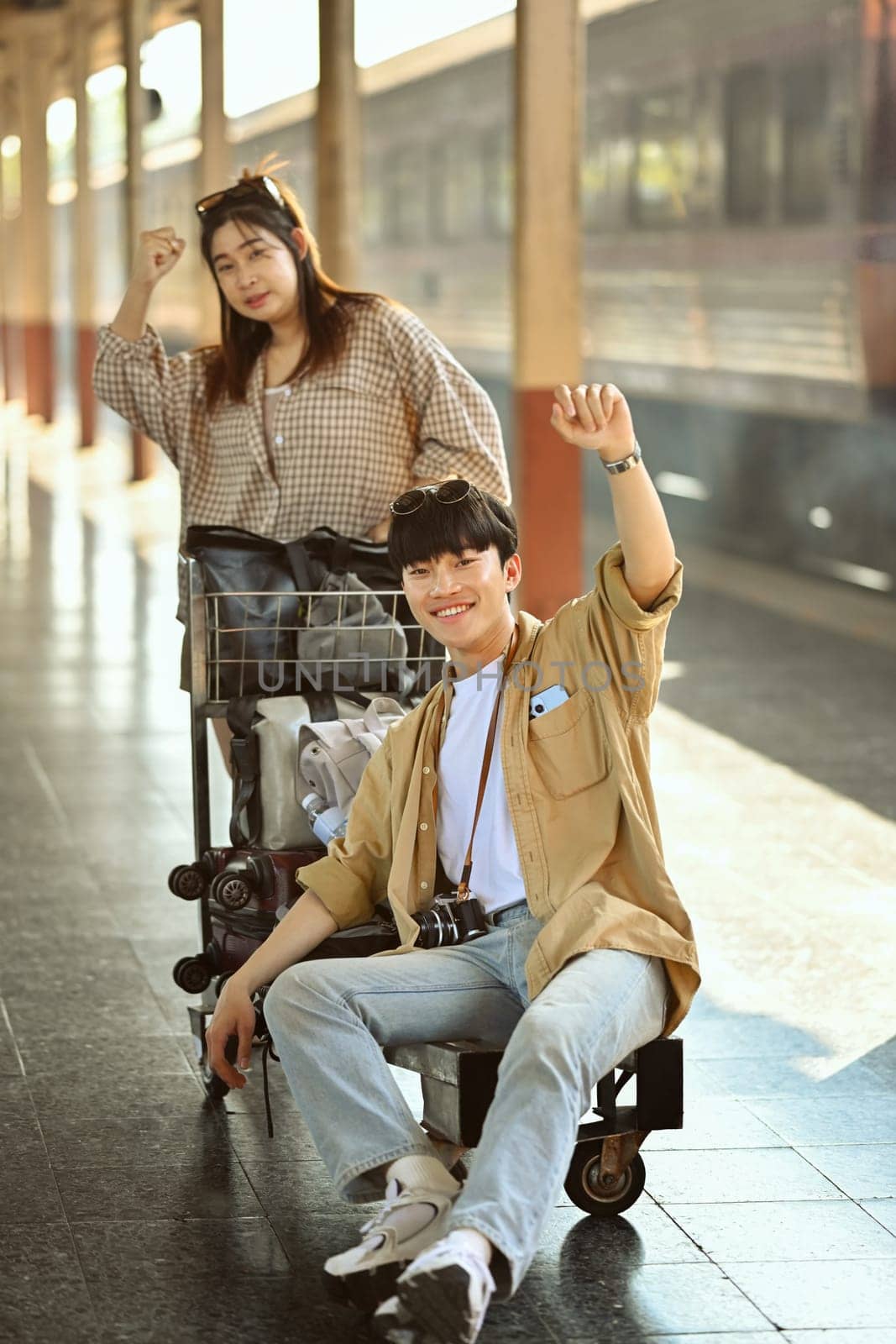 Happy young couple excited about their vacation trip standing in train station. Travel and lifestyle concept.