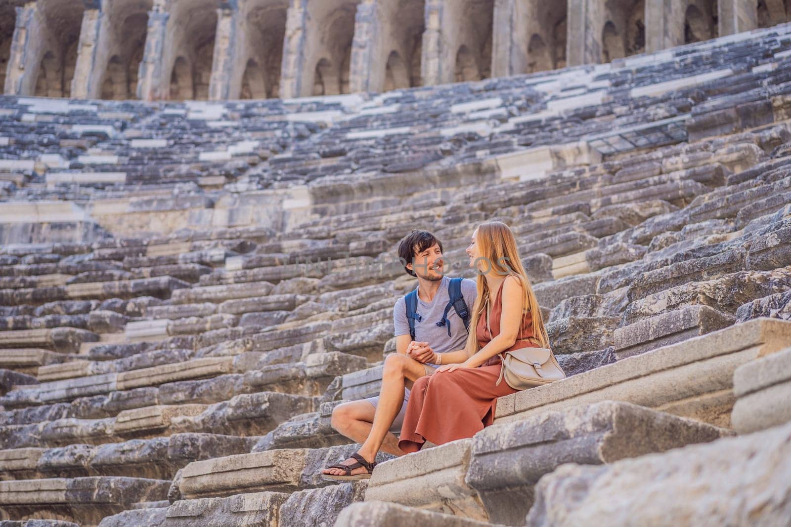 Happy couple man and woman tourists explores Aspendos Ancient City. Aspendos acropolis city ruins, cisterns, aqueducts and old temple. Aspendos Antalya Turkey. turkiye.