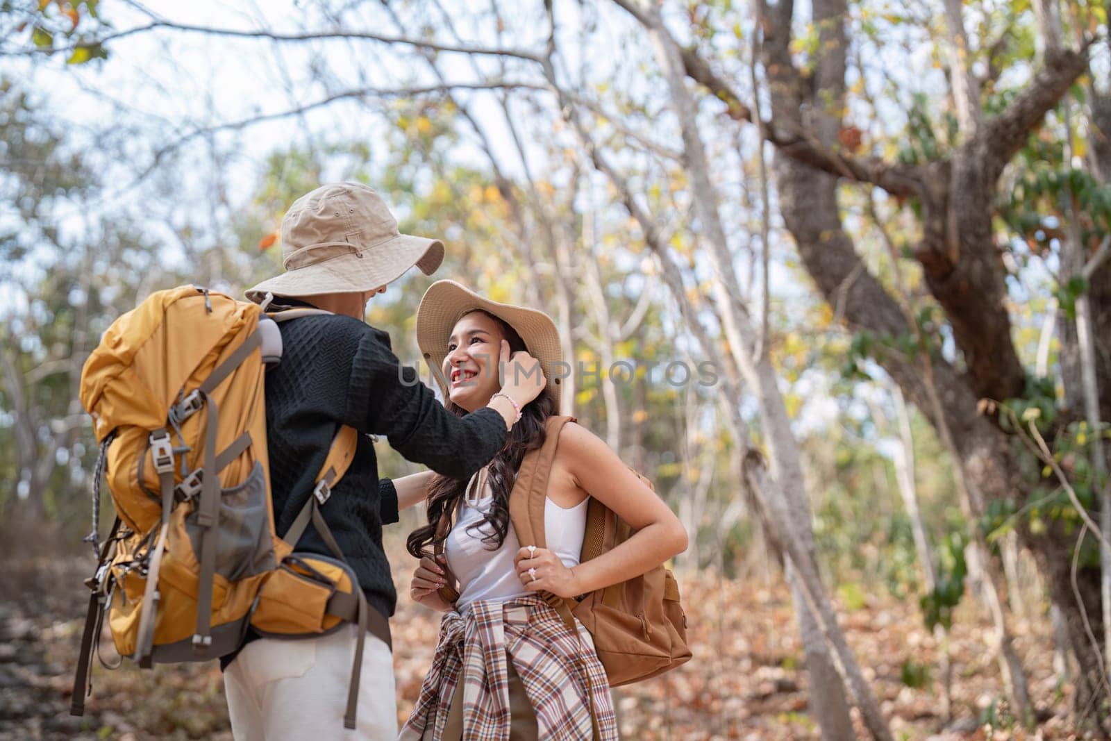 Cheerful romantic lesbian couple traveler with backpack on their backs go hiking through the forest in the mountains in summer by nateemee