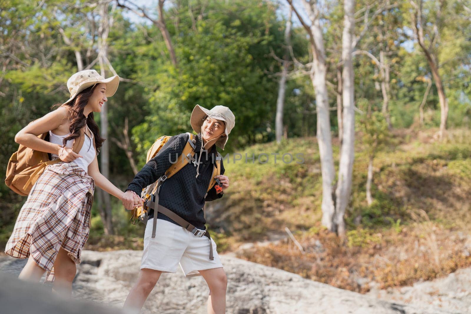 Cheerful romantic lesbian couple traveler with backpack on their backs go hiking through the forest in the mountains in summer by nateemee
