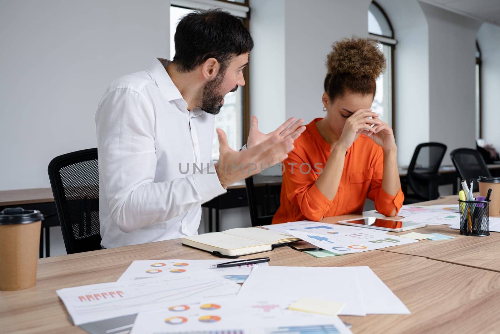 Two young businesspeople smiling while working with wireless technology in a modern workspace.