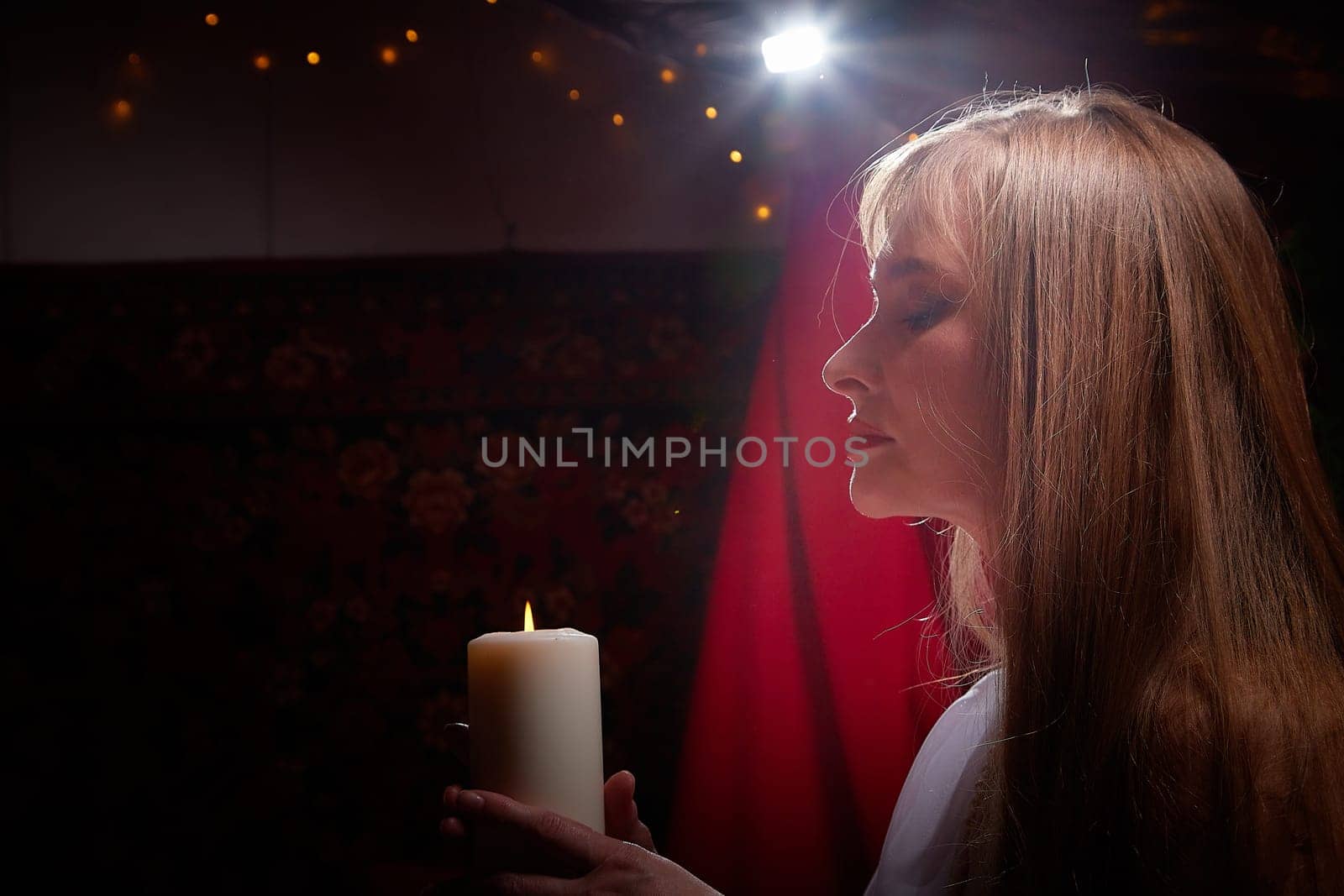 Beautiful arabian girl with candles in red room full of rich fabrics and carpets in sultan harem. Photo shoot of woman an oriental style odalisque. Model poses in sari as caring wife and hostess