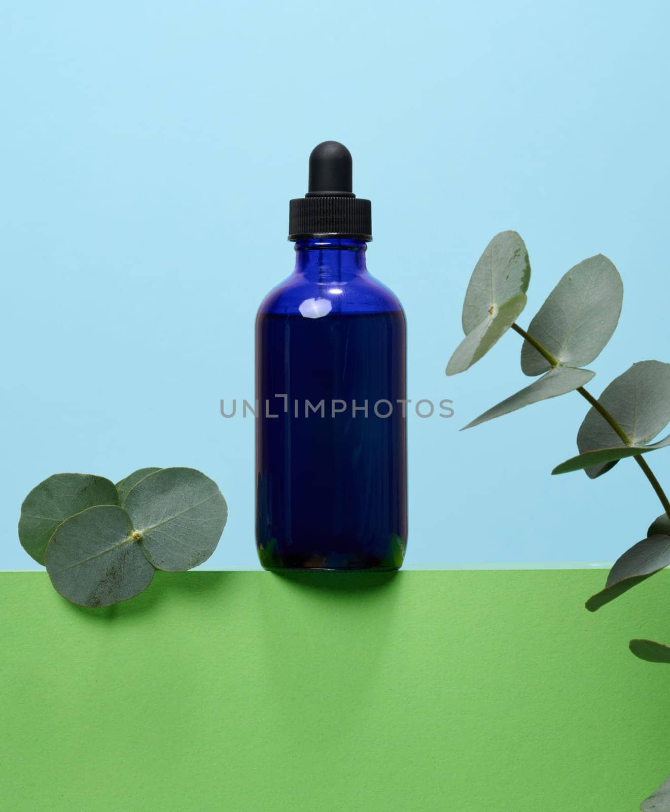 A glass blue bottle with a dropper on a blue background, a container for cosmetic products.  by ndanko