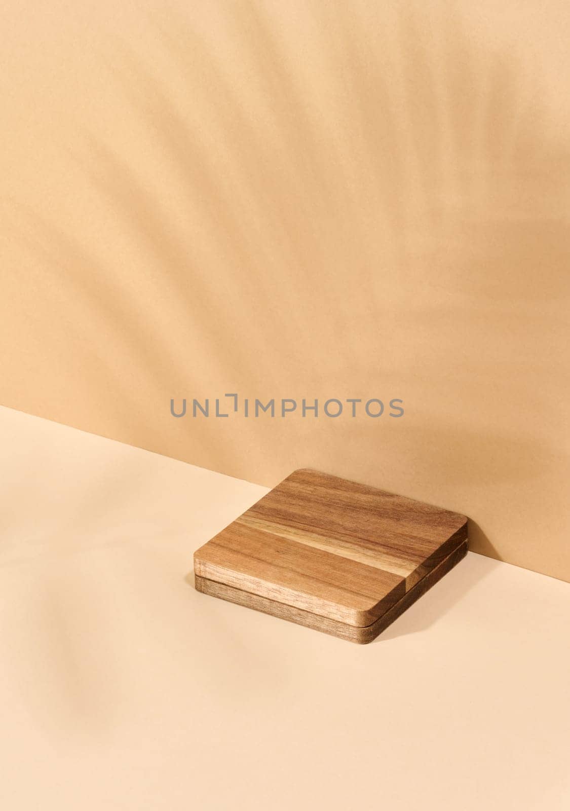 Wooden platform, shadow from a palm leaf on a brown background. Place for displaying cosmetics by ndanko