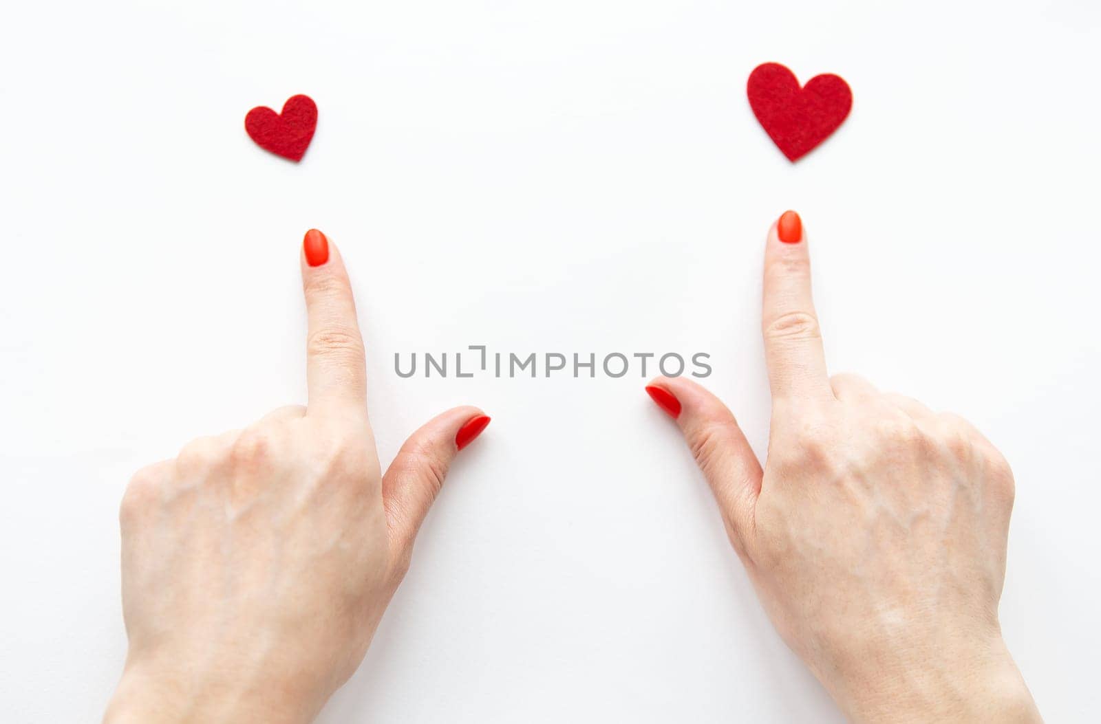 The girl shows her hand to a small and large red heart. The concept of care and love