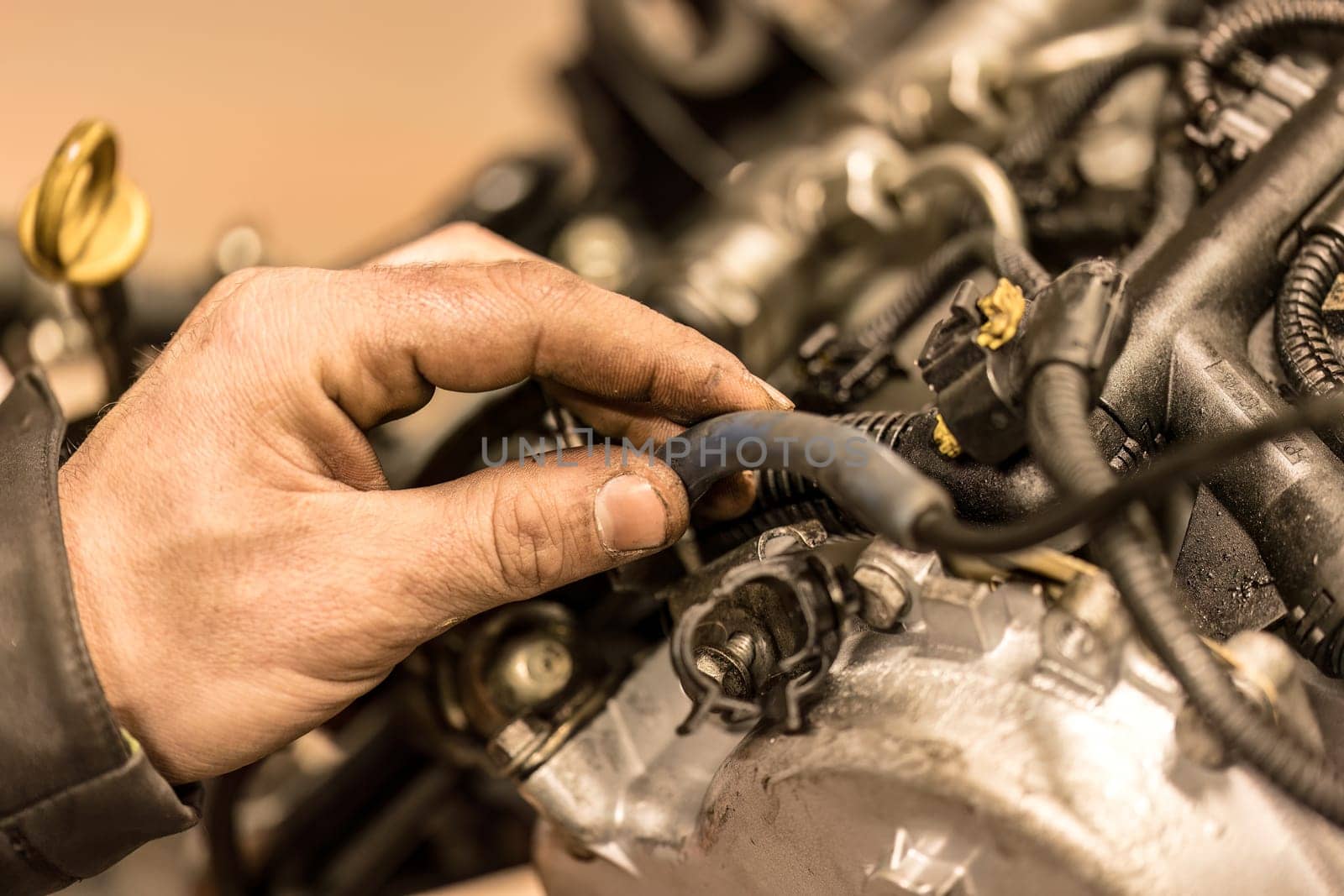 Photo capturing a mechanic's grimy hand on a car engine, highlighting the reality of automotive work.