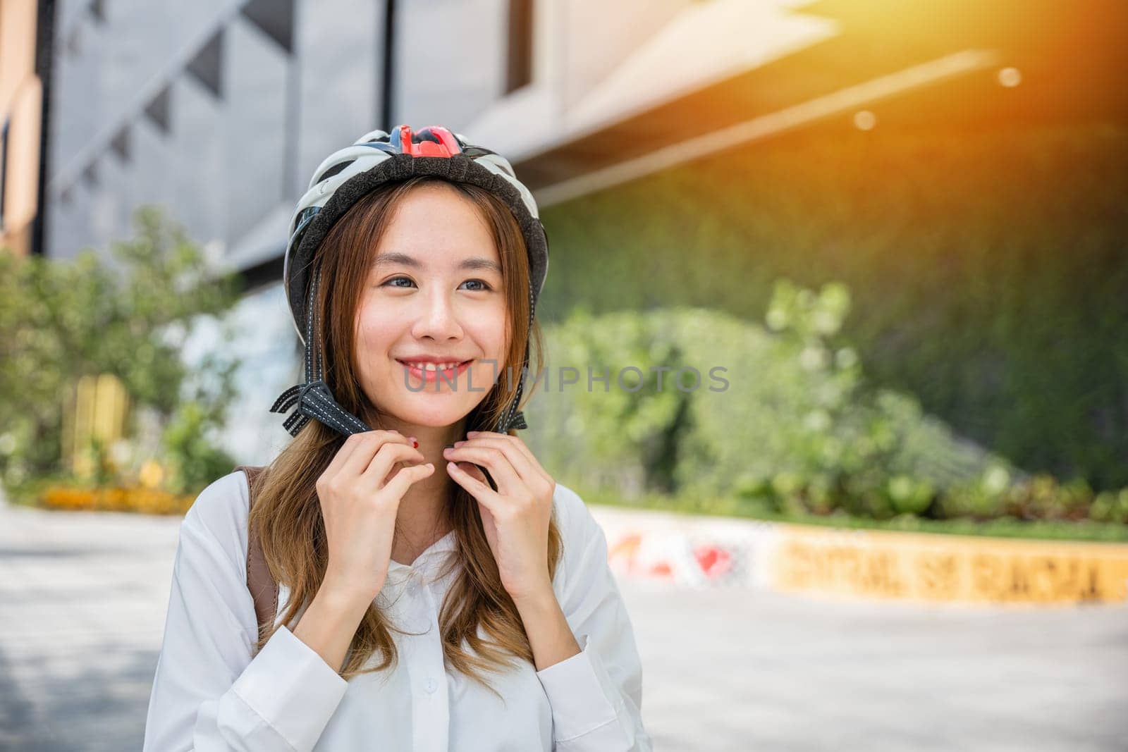 Asian young businesswoman putting biking helmet prepared cyclists go to work, Close up beautiful woman wearing helmet exercise outdoors, Transport Save Energy concept