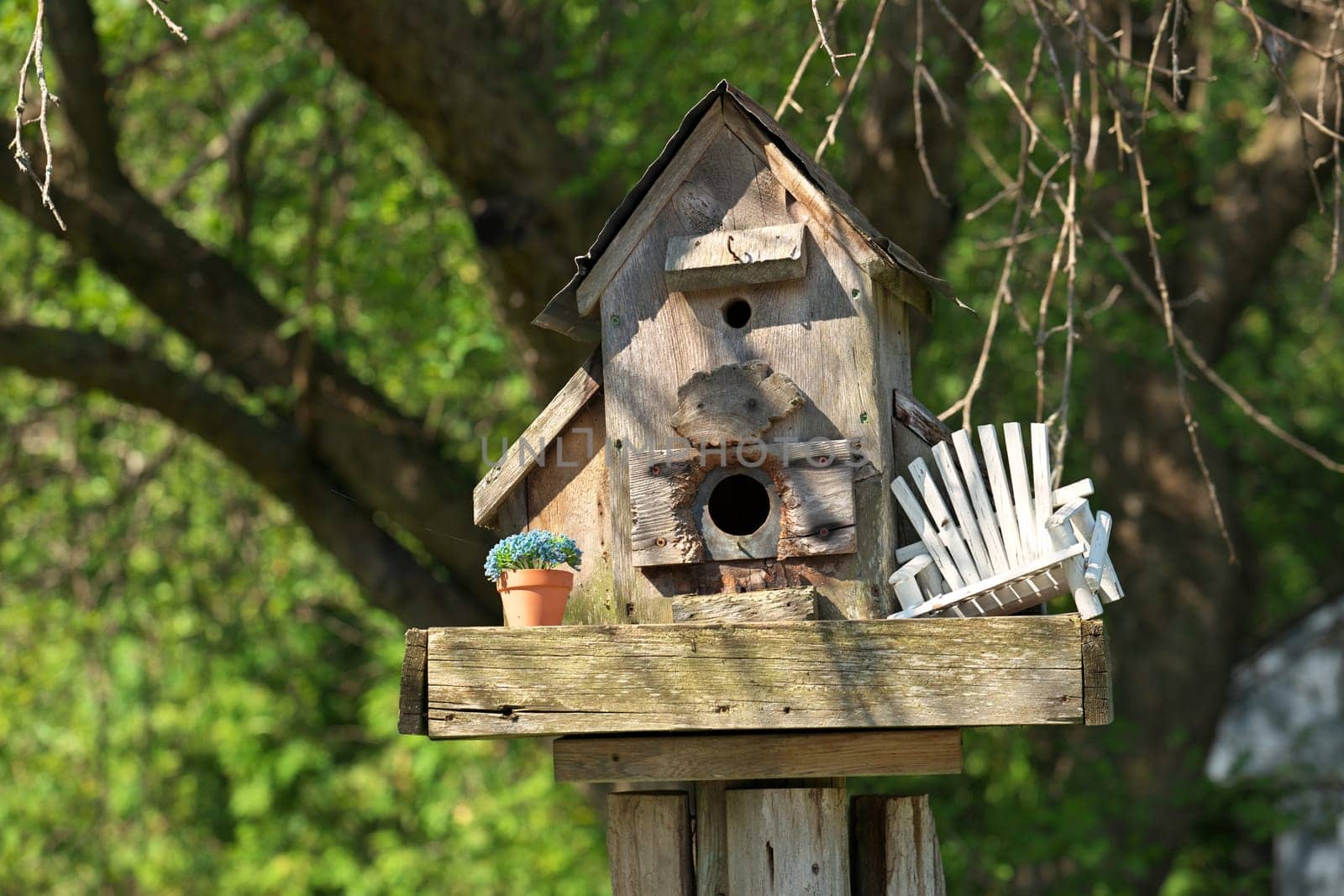 Whimsical Handmade Birdhouse in Garden with Miniature Chair and Potted Plant. High quality photo