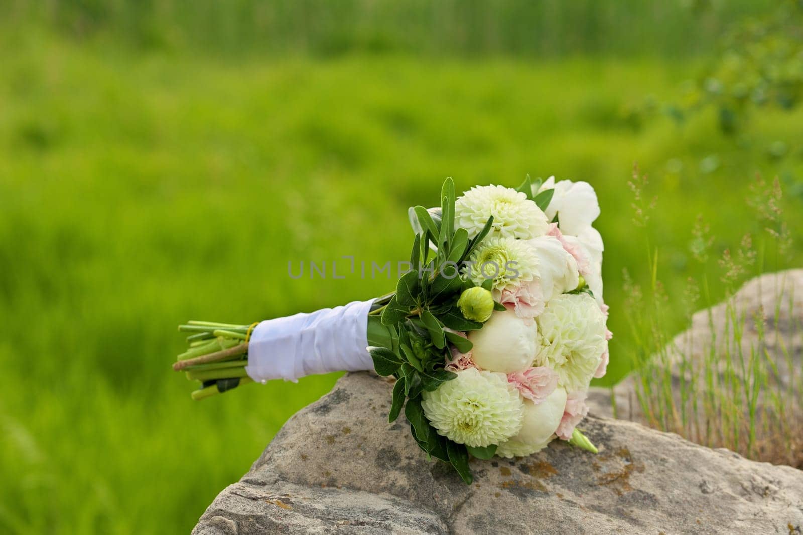 Beautiful Wedding Bouquet Resting on Granite Boulder in Sunshine in Summer. High quality photo