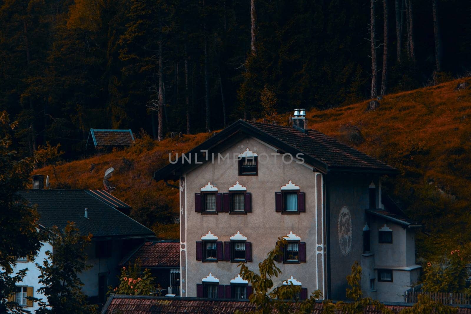 Autumnal Alpine Elegance: A Heritage House Against the Fiery Hues of a Forested Hillside. High quality photo
