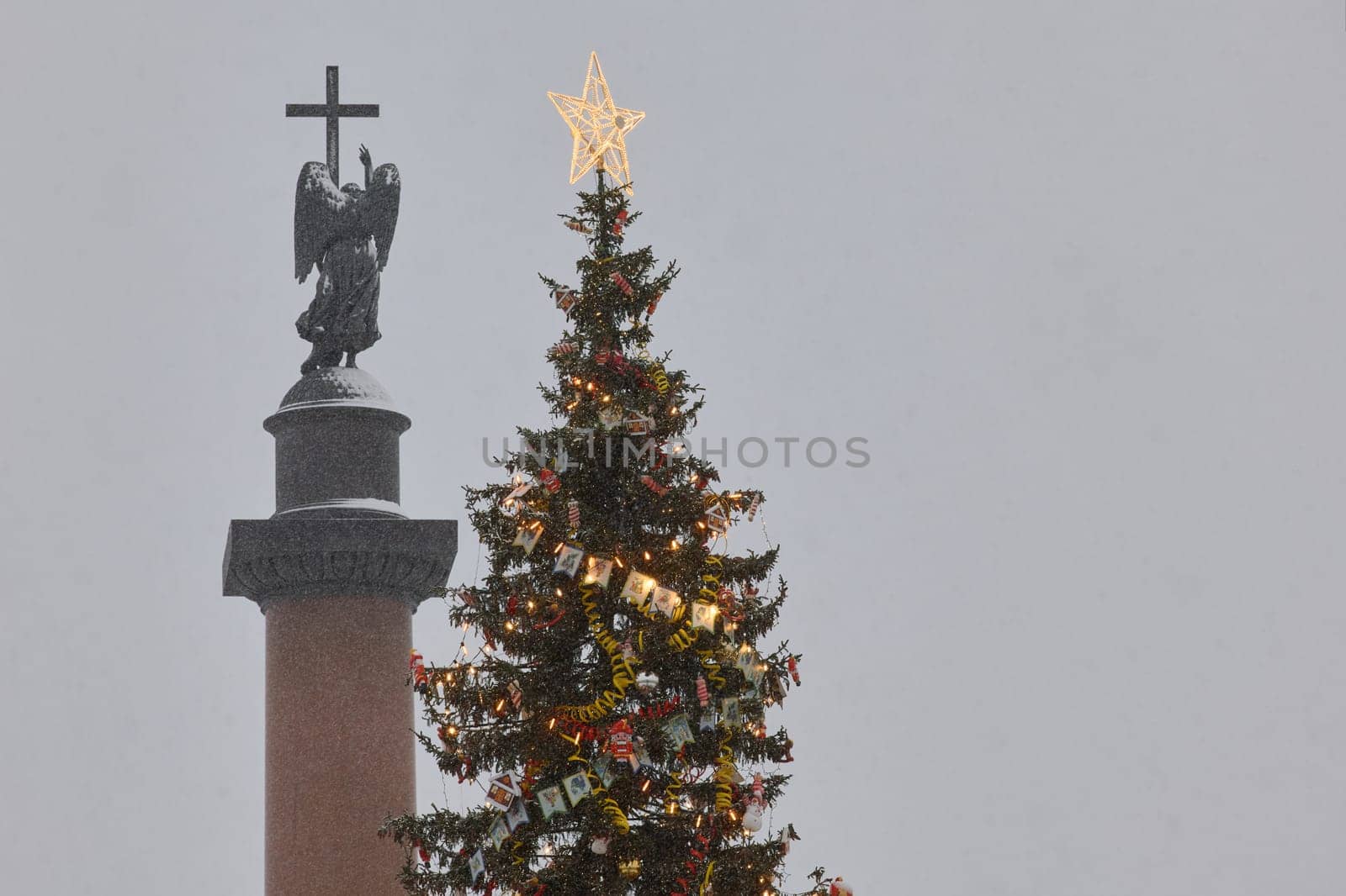 Russia, St.Petersburg, 30 December 2023: The main Christmas tree shimmers with lights of decorations, Alexander column with angel with wing and cross, the central Palace square during the snowfall by vladimirdrozdin