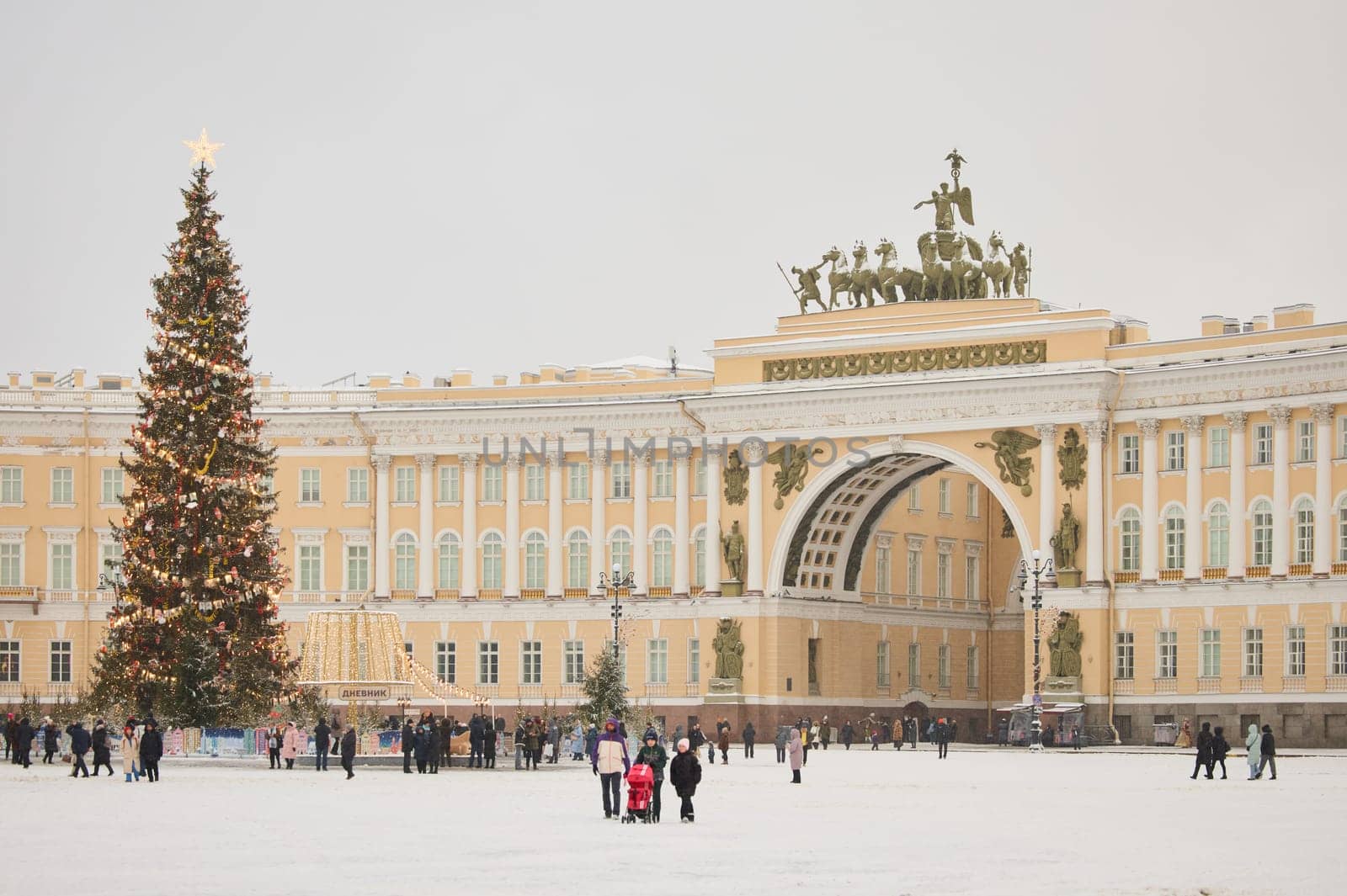 Russia, St. Petersburg, 30 December 2023: The main Christmas tree shimmers with lights of decorations on the central Palace square during the snowfall, Arch of the General Staff, a lot of people by vladimirdrozdin