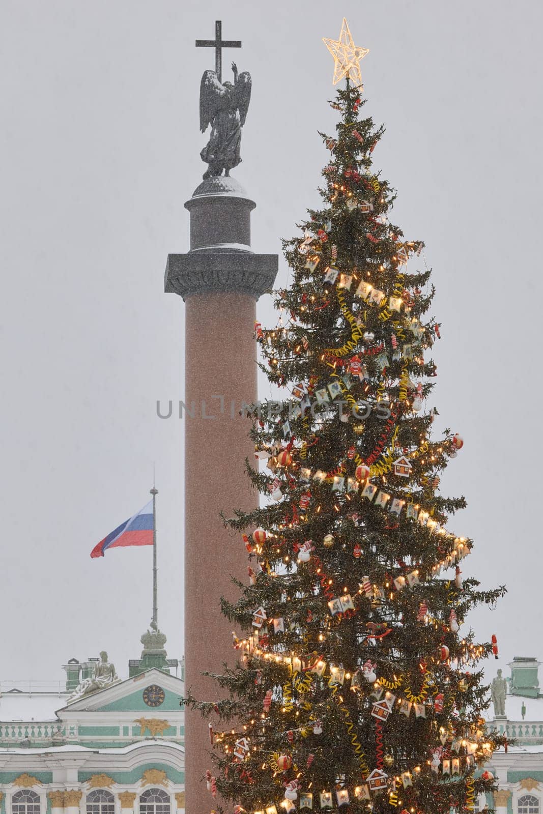 Russia, St. Petersburg, 30 December 2023: The main Christmas tree shimmers with decorations, Alexander column with angel with cross, the Palace square during the snowfall, national flag of Russia. High quality 4k footage