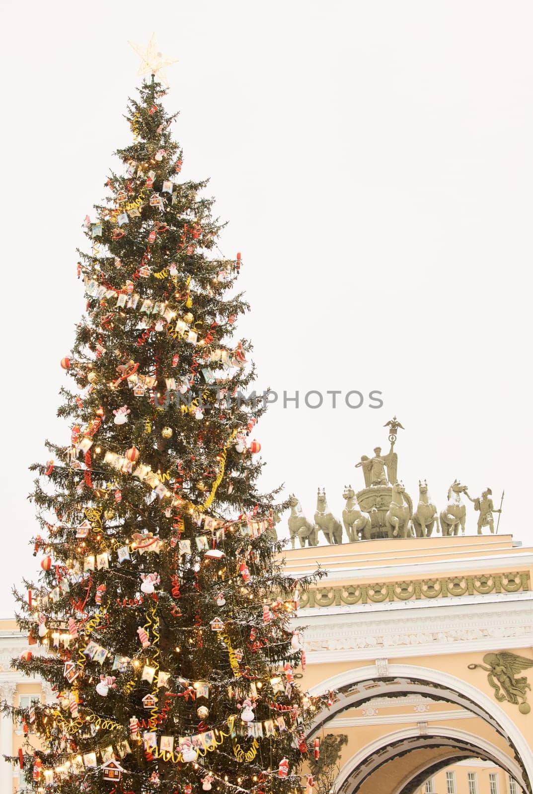 The main Christmas tree shimmers with lights of decorations, the central Palace square of the city decorated for the celebration during the snowfall, Arch of the General Staff, flag of Armed Forces by vladimirdrozdin