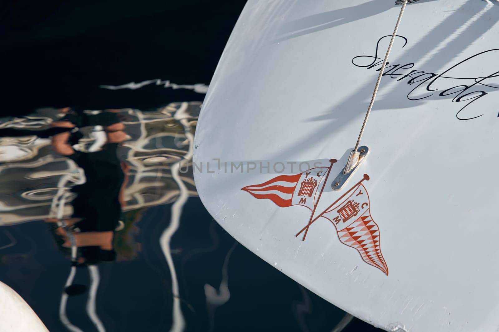 Monaco, Monte-Carlo, 26 October 2022: Logo of new Yacht Club on glossy board of moored sail boat, azure water, tranquillity in port Hercules at sunny day by vladimirdrozdin
