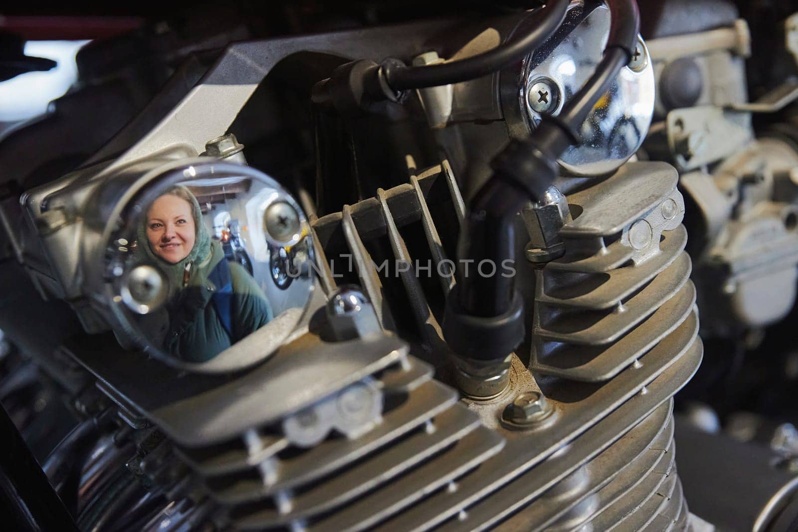 A visitor is reflected in the engine of a vintage motorcycle in Denmark