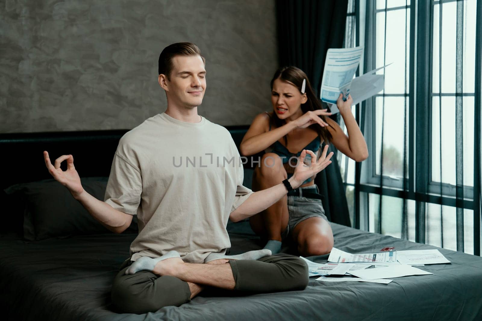 Young man doing mindfulness meditation ignoring his wife. Unveiling by biancoblue