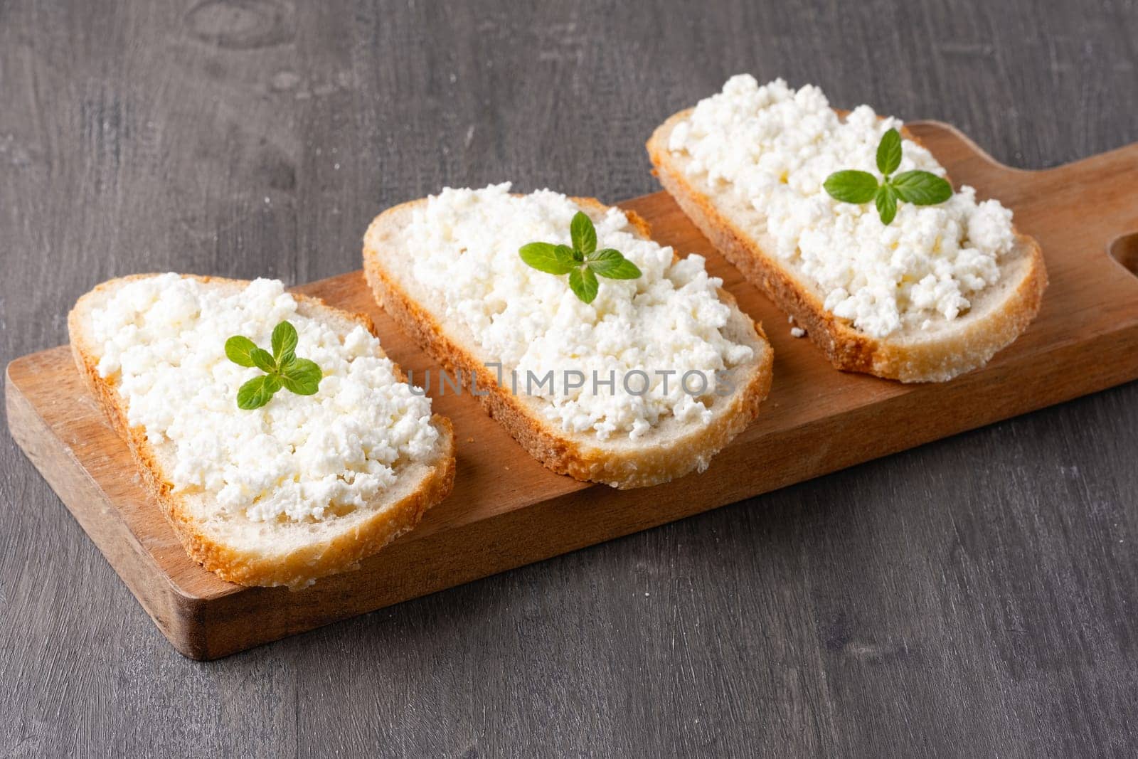 Bread with curd cheese on wooden board by NataliPopova