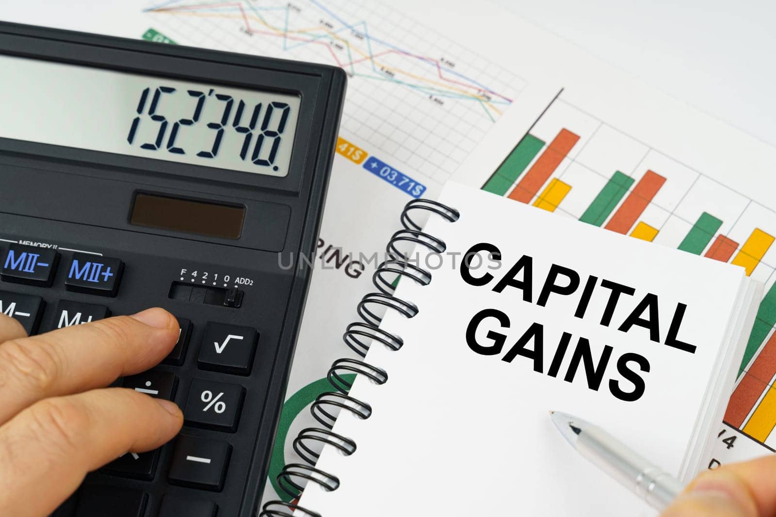 Business concept. On the table there is a calculator, reports with graphs and a notepad with the inscription - Capital gains