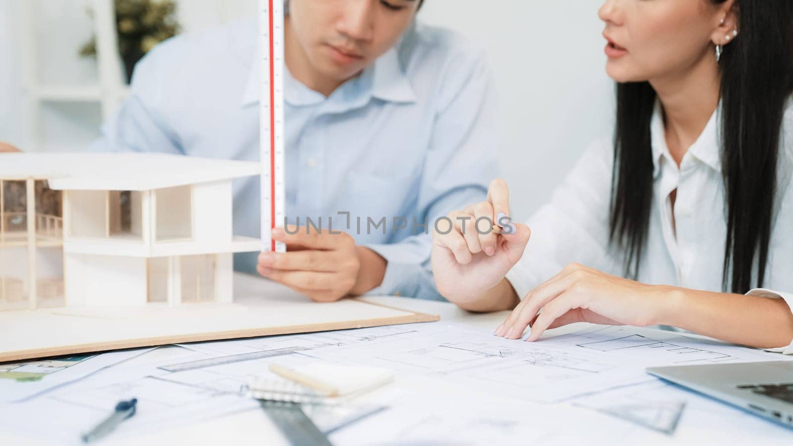 Professional engineer measures house model while skilled designer writes down in blueprint. Work together, collaboration, cooperate. Creative design and team working concept. Closeup. Immaculate