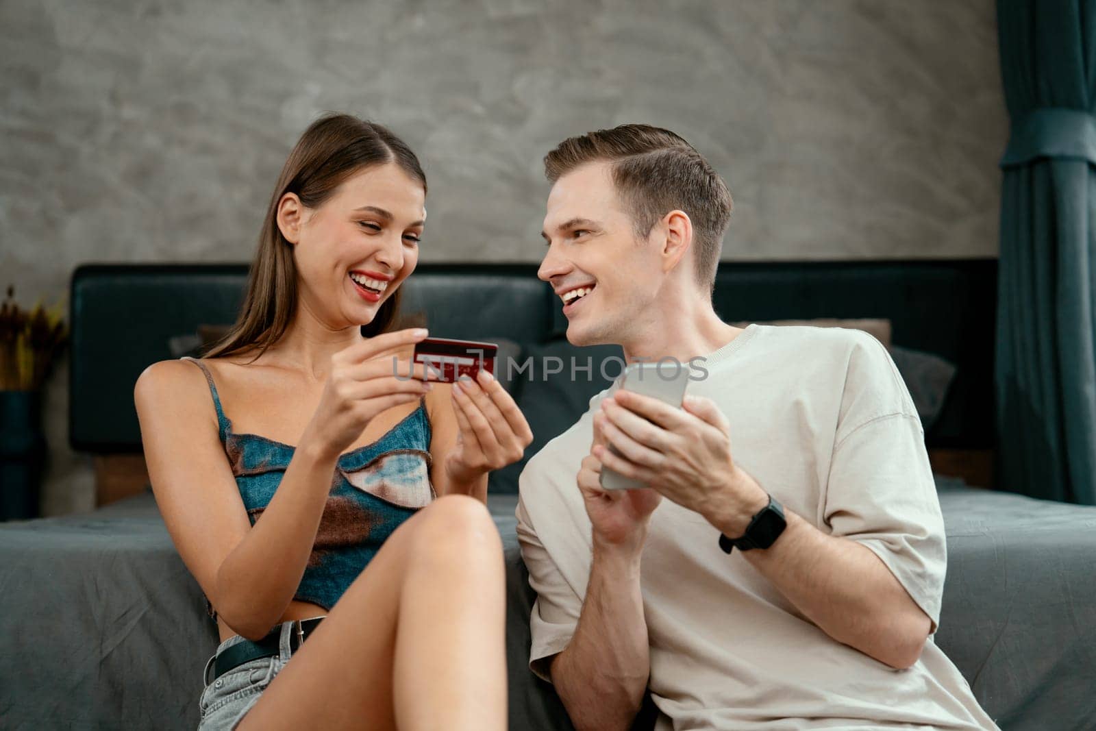 Young couple sit in the bed room using online payment app. Unveiling by biancoblue