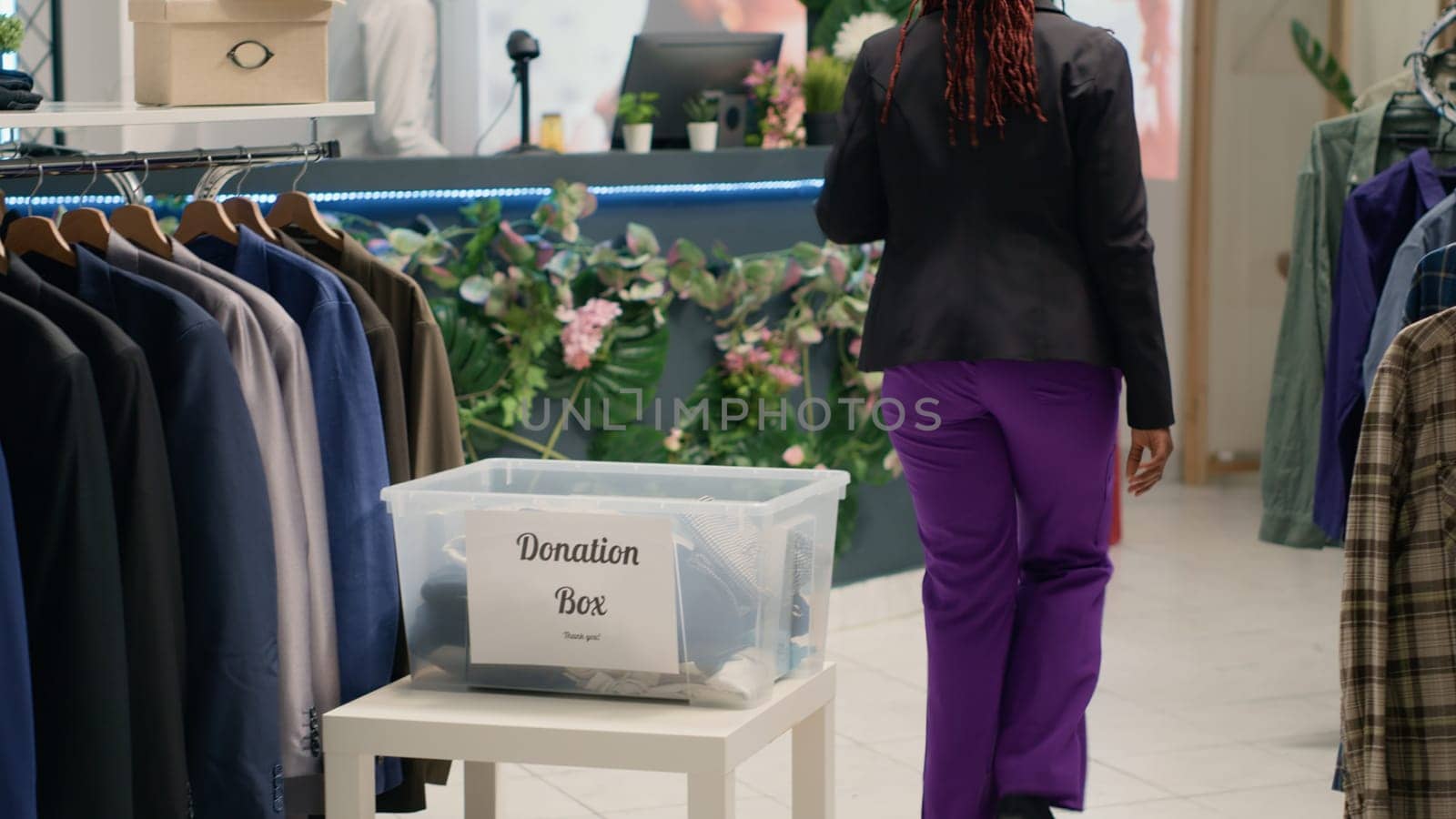 BIPOC shoppers in fancy fashion boutique donating their clothes for good cause. Customers placing garments in donation box, doing humanitarian gesture in premium clothing store