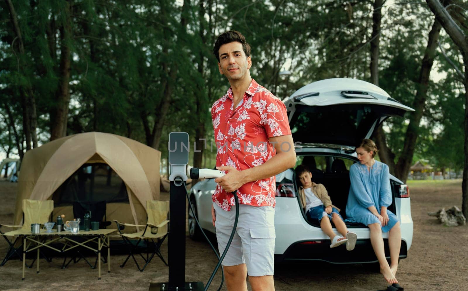 Lovely family recharge EV car with EV charging station in campsite. Perpetual by biancoblue