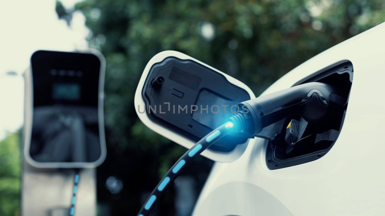 Electric car plugged in with charging station in eco green park. Peruse by biancoblue